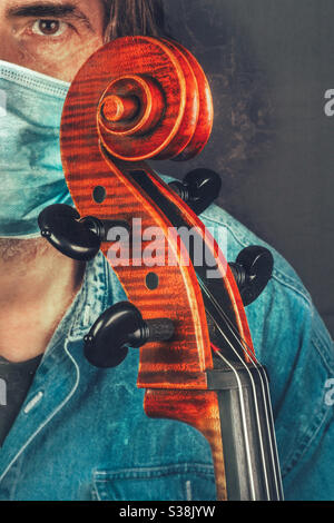 Männlich weiß kaukasischen Musiker trägt Gesichtsmaske hält sein Cello Stockfoto