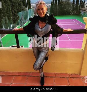 Frau im silbernen Catsuit über dem rosa Tennisplatz bei Pikes Ibiza Stockfoto