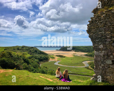 Zwei junge Mädchen genießen den Blick über Three Cliffs Bay von Pennard Castle, Gower, Swansea, Wales, August. Stockfoto