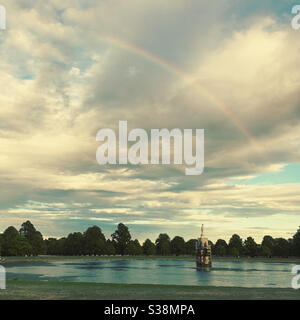 Der Diana-Brunnen im Buschy Park mit stimmungsvollem Himmel und Regenbogen an einem Sommerabend. Vereinigtes Königreich Stockfoto