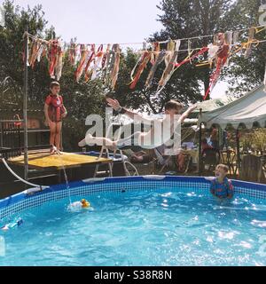 Elfjähriger Junge, der einen Bauchflop in einen Gartenpool durchführt. Medstead Hampshire, England, Vereinigtes Königreich. Stockfoto