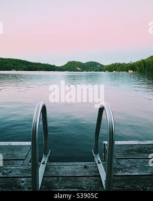 Dock und Leiter am Rande des ruhigen nördlichen Ontario See in muskoka Cottage Land. Sommer 2020. Stockfoto