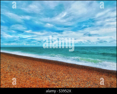 Ein ruhiger Blick auf kleine Wellen auf einem einfallenden Gezeitenschlag auf einem Kiesstrand. Ein friedliches Bild, das Zufriedenheit weckt. Bildnachweis - ©️ COLIN HOSKINS. Stockfoto