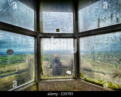 Figur des Kindes durch Graffiti bedeckte Fenster in der gesehen Laterne auf der Spitze des Jubilee Tower auf Darwen Moor Über Blackburn in Lancashire Stockfoto