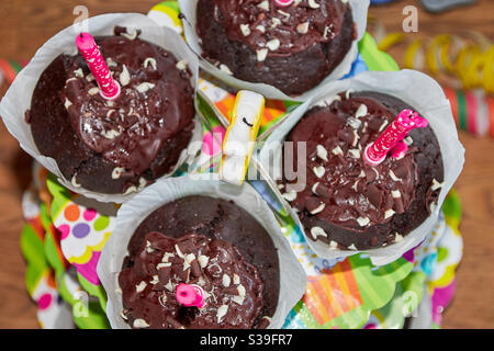 Vier Geburtstags-Schokoladen-Muffins mit Kerzen und farbenfroher Dekoration Eine Tabelle von oben Stockfoto