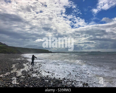 Mann beim Angeln auf Porth Pistyll, Nordwales in rauer See, August. Stockfoto