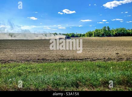 Ein Traktor fährt in Connor Township in Aroostook County, Maine, Mitte August 2020 durch ein Feld mit einer großen Staubwolke dahinter. Das Gebiet erlebt eine schwere Dürre Stockfoto