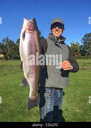 Fischer mit einer großen 9lb Regenbogenforelle, Testwood Forellenfischerei, Hampshire, England, Vereinigtes Königreich. Stockfoto