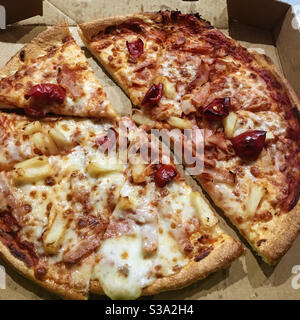 Fast Food, Take-Away-Pizza in einer Pappschachtel, mit Mozzarella-Käse, rotem Paprika und Ananas bedeckt, heiß und verzehrfertig, lecker! Stockfoto