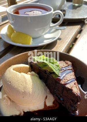 Schokoladenbrownie und Eis mit einer Tasse Tee mit Zitrone Stockfoto