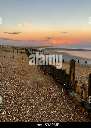 Wellenbrecher am Strand bei Sonnenuntergang Stockfoto