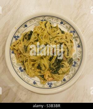 Garnelen und frische Tagliatelle mit cremiger Zitronenpesto-Sauce, Spinat und Tomaten. Stockfoto