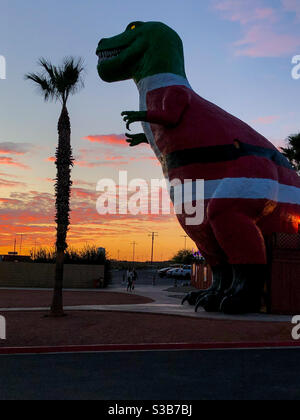 Palm Springs, USA. November 2020. Der Cabazon Dinosaurier trägt einen Weihnachtsanzug außerhalb von Palm Springs bei Sonnenuntergang. Stockfoto