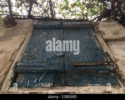 Altes Holzfenster, gealtert und durch Zeit und Verlassenheit zerfallen, im traditionellen Viertel Plaka, in Athen, Griechenland, Europa. Stockfoto
