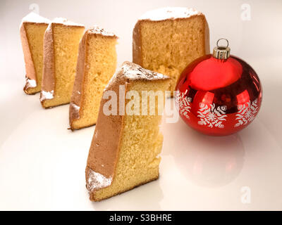 Pandoro, typisch italienischer Weihnachtskuchen, Scheiben mit Puderzucker und roter Weihnachtskugel Stockfoto