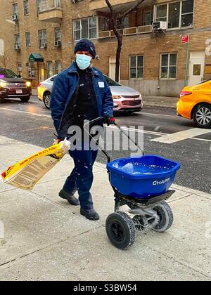 Fröhliche Arbeiter salzen auf dem Bürgersteig in der 36th St & Park Avenue in Murray Hill, Midtown, Manhattan, während ein Schneesturm in New York City hereinzieht. Stockfoto