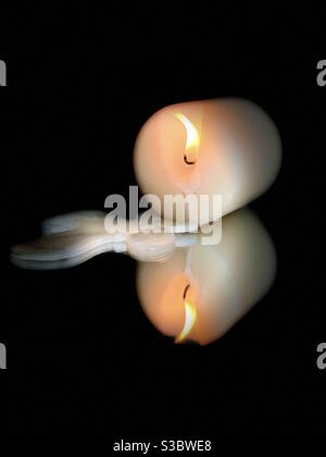 Kerze brennend mit tropfendem Wachs auf schwarzem Hintergrund gespiegelt Oberfläche Stockfoto