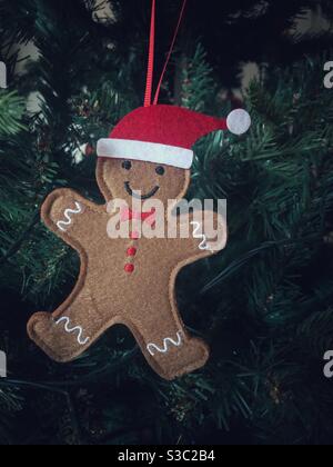 Ein glücklicher Lebkuchen Mann oder Person Weihnachtsbaum Dekoration hängen Auf einem Weihnachtsbaum mit Weihnachtsmann Hut auf Stockfoto