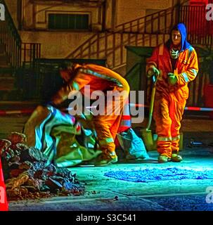 Arbeiter reparieren eine Straße in einer kalten Winternacht in New York City. Stockfoto