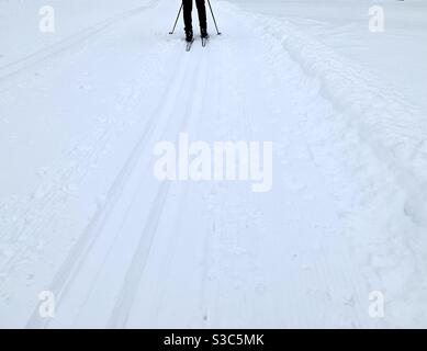 Langlaufloipe für klaasische und Skating-Stile. Im Hintergrund die Silhouette einer Person dlidimg auf dem Trail. Im Vordergrund befindet sich viel Platz für Kopien. Stockfoto