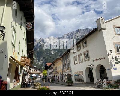 Straße in der deutschen Stadt Mittenwald mit bunten traditionellen Häusern und Blick auf die Alpen. Stockfoto