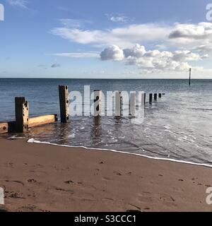 Holzpfosten auf einem Strand im Meer mit einem Metallstange für eine Seeverteidigung in Devon England Stockfoto