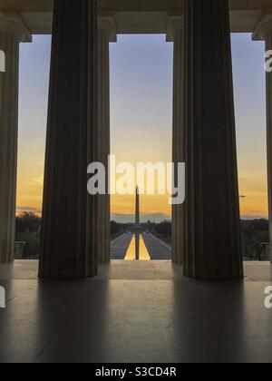 Die Sonne geht über dem Washington Monument und dem reflektierenden Pool in Washington DC auf, wie man es vom Inneren des Lincoln Memorial aus sieht. Stockfoto