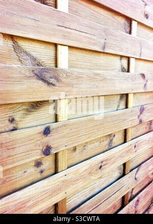 Seitlich abgewinkelte perspektivische Ansicht eines hölzernen Gartenzaun mit Rote und orange helle und sichtbare Knoten auf der Holzarbeit Stockfoto