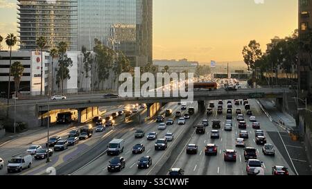 LOS ANGELES, CA, NOV 2020: Blick nach Süden auf den Verkehr auf der CA-110 Autobahn vorbei Downtown Büros, Hotels und Wohnungen bei Sonnenuntergang. Bus auf Brücke Stockfoto