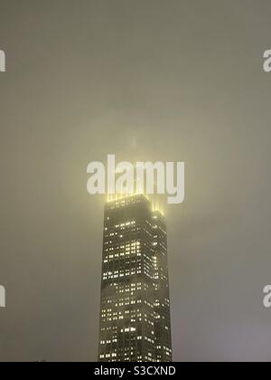 Das Empire State Building leuchtet wie ein Wächter in der gedämpften Unruhe eines dunklen verschneiten Winterabends in New York City, USA Stockfoto