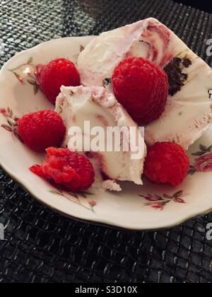 Nahaufnahme eines Eis-Dessert und Himbeeren auf Feines Porzellan Stockfoto