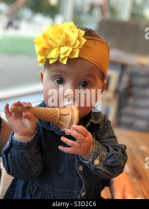 Baby Mädchen essen ihr Eis-Kegel Stockfoto