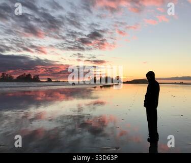 Silhouette des Mannes Sonnenuntergang Strand Blick mit Surfern in der Hintergrund Tofino BC Stockfoto
