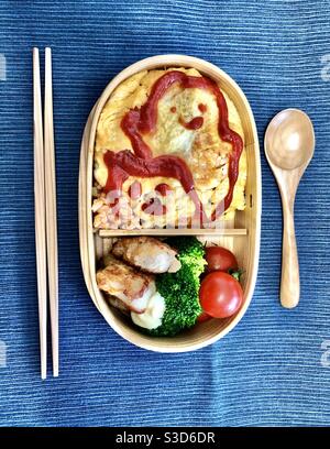 Hausgemachte Bento-Box Mittagessen in einer Zedernholzschachtel Eine blaue Tischdecke Stockfoto