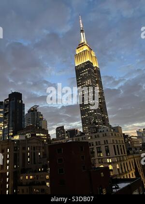 Silhouette des Empire State Building mit golden weißen Lichtern gegen den Dämmerungshimmel mit geschwollenen grauen Wolken vor einem Sturm, New York City, USA Stockfoto