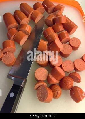 Geschnittene Hotdogs und ein Metzgermesser auf einer Wohnküche Schneidebrett, USA Stockfoto