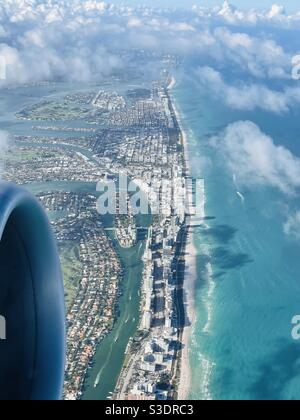 Flauschige weiße Wolken werfen Schatten auf das türkisfarbene Meerwasser von Miami Beach, Florida, USA unten, wie aus einem Passagierfenster einer Boeing 737 bei Abflug vom Miami International Airport gesehen Stockfoto