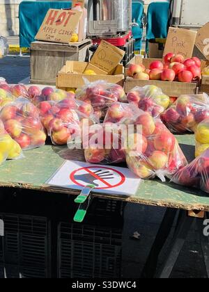 Tüten mit lokal angebauten rosafarbenen Lady-Äpfeln an einem Obststand auf dem Union Square Farmers Market, Manhattan, New York City, USA, werben auch für heißen Apfelwein & frische Quitte. Stockfoto