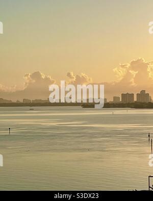 Sonnenaufgang in Miami, Florida, USA über stillen Ozeangewässern mit wabenden Wolken und Hochhäusern am Horizont Stockfoto