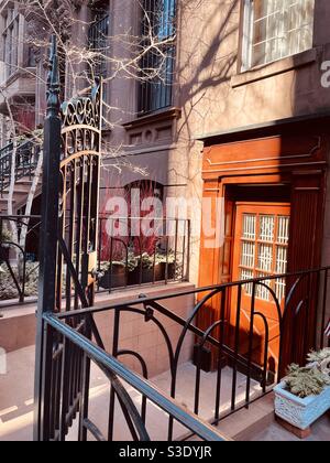 Eine wunderschöne orangefarbene Holztür in einer der schönsten Straßen Manhattans, 131 35th St. in Murray Hill, New York City, USA Stockfoto