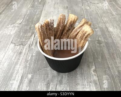 Frisch gebratene Churros in Zimtzucker getaucht und dazu serviert Eine Karamellsauce Stockfoto