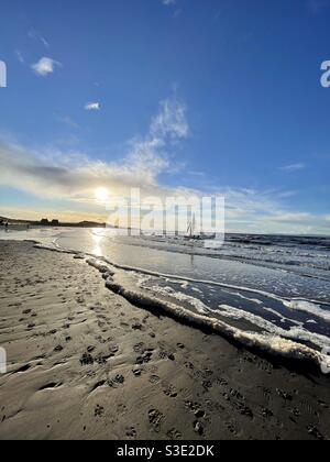 Sonniger Winterblick auf das Meer am Strand von Prestwick, Ayrshire, Schottland mit einer Yacht. Stockfoto