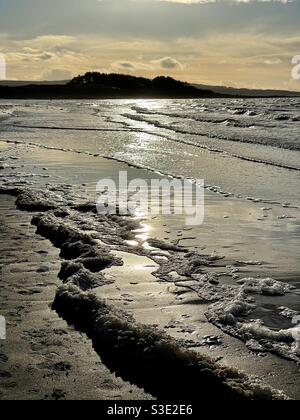 Wunderschöne Panoramasicht auf den Sonnenuntergang über dem Ozean vom Prestwick Beach, Ayrshire, Schottland auf Firth of Clyde, Westküste mit schaumigen schäumenden Wellen im Vordergrund. Stockfoto