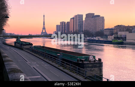 Paris, Frankreich. März 07. 2021. Die Stadt bei Sonnenaufgang. Blick auf die Uferseite der seine. Eiffelturm im Hintergrund. Moderne Gebäude des Beaugrenelle Viertels. Boote, Lastkähne, im Vordergrund Stockfoto