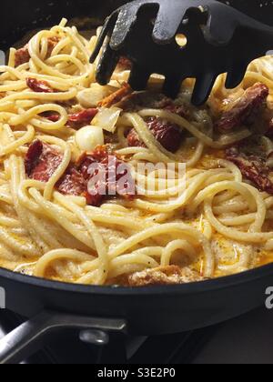 Nahaufnahme einer Nudelgabel mit italienischem Feinschmecker Vorspeise aus sonnengetrockneten Tomaten in einer Sahnesauce auf Spaghetti Nudeln Stockfoto