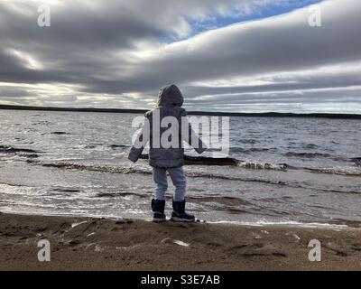 Kleiner Junge, der an der Seite eines Loch in spielt Die Highlands Stockfoto