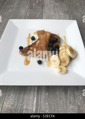 Zimt French Toast serviert mit Banane und Heidelbeeren in Scheiben geschnitten und Garniert mit Ahornsirup Stockfoto