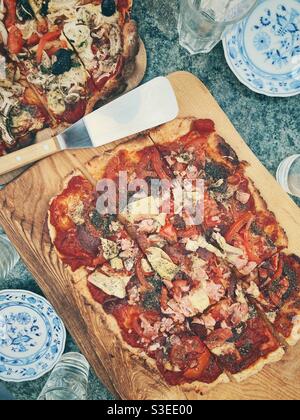 Hausgemachte Pizza auf einem hölzernen Servierbrett Stockfoto