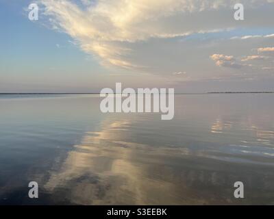 Flauschige weiße Wolken, die sich auf das ruhige Lorbeerwasser spiegeln Stockfoto