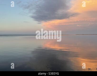 Farbenfrohe Sonnenwolken, die sich auf das ruhige Bay Water spiegeln Stockfoto